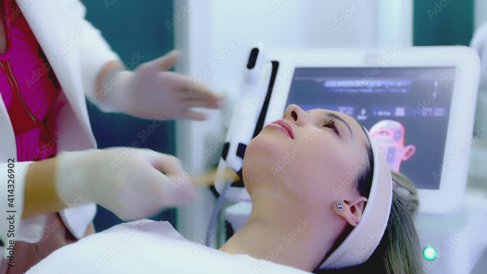 Beautician applying a skin treatment lotion on a young woman's face before an ultrasonic procedure. Beautician applying a skin treatment lotion on a young woman's face before an ultrasonic procedure.