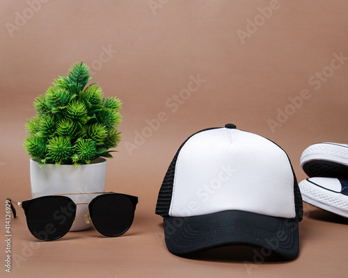 Blank baseball caps are used for design mockups. The hat on the side of an old camera and sunglasses. Plain hat isolated on brown background. Take a picture of a hat ready to be displayed. Mockup hat. photo