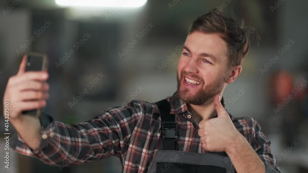 smiling young man in work uniform taking a selfie on the phone smiling young man in work uniform taking a selfie on the phone