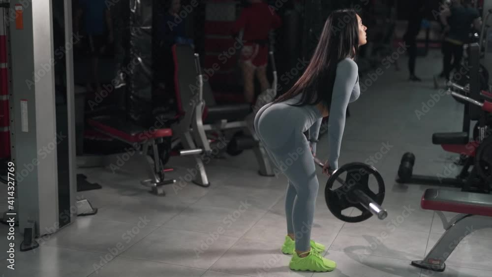 curvy sports girl doing exercises with a barbell