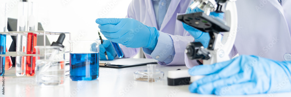 Attractive young scientist team in lab coat and safety goggles working with analysing test trial or investigations with test tubes in laboratory. Attractive young scientist team in lab coat and safety goggles working with analysing test trial or investigations with test tubes in laboratory.