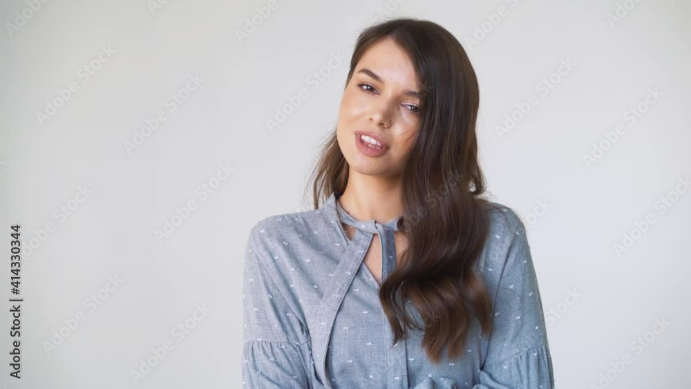 Smiling attractive young adult woman model looking at camera, happy beautiful brunette lady professional pretty face dental smile posing stand alone indoors, slow motion close up view portrait Smiling attractive young adult woman model looking at camera, happy beautiful brunette lady professional pretty face dental smile posing stand alone indoors, slow motion close up view portrait
