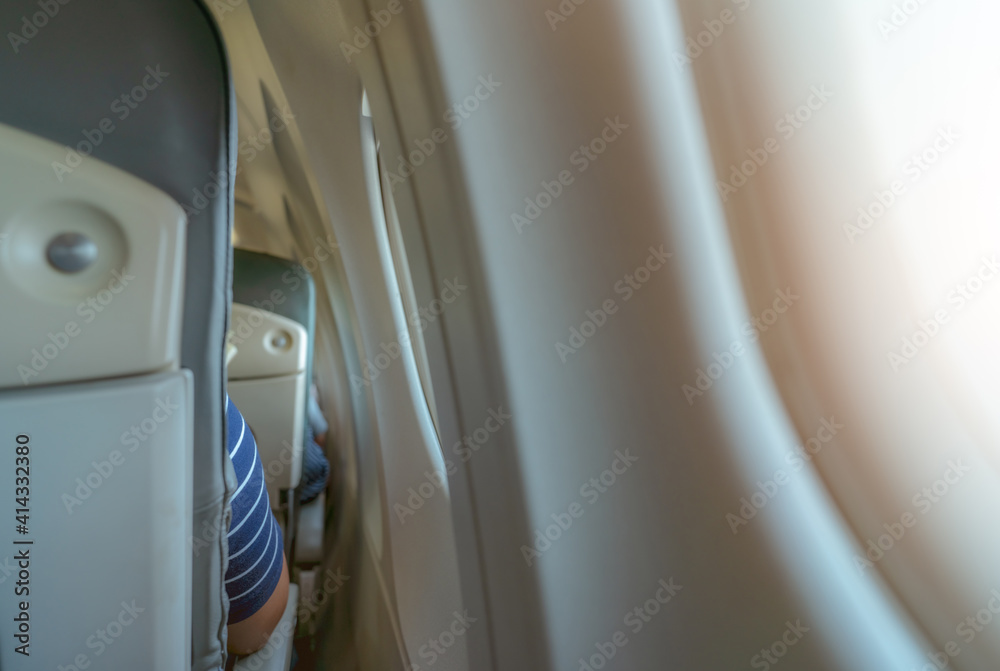 Rearview of airplane seat near plane window. Economy class airplane. Inside of commercial airline. Small space between passenger economy seat and window of airplane. Seat with armchair. Leather seat. Rearview of airplane seat near plane window. Economy class airplane. Inside of commercial airline. Small space between passenger economy seat and window of airplane. Seat with armchair. Leather seat.