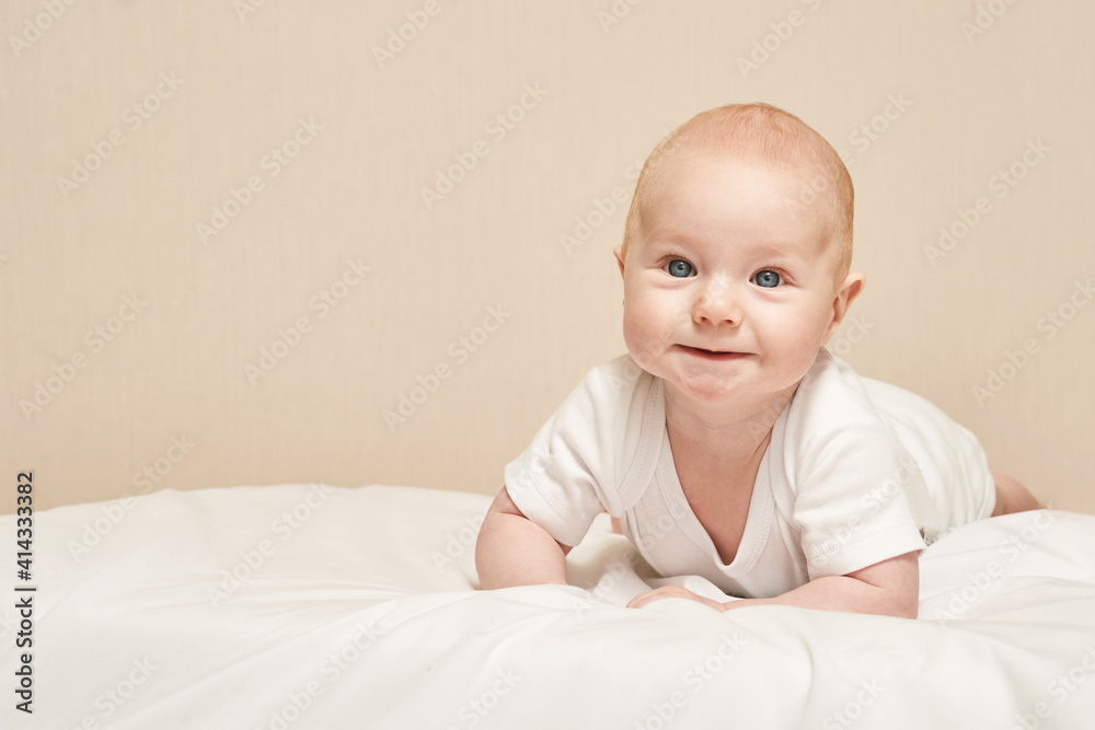 Cute small boy lying at bed. Childhood concept. Light background. Smiling child. Happy emotion. Copyspace. Stay home. Mockup. White clothes