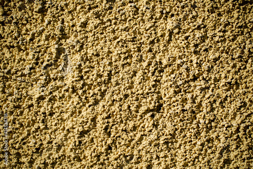 Rough wall texture under the strong sun light. Yellow wall background. photo