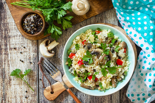 Diet food vegan concept. Vegan salad with couscous and champignons on a wooden table. Top view flat lay.