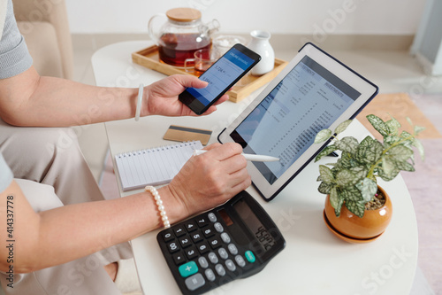 Hands of senior woman checking investment account via application on tablet computer and buying new stocks and receiving dividends