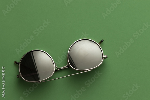 Fashionable sunglasses. gold-colored metal, on a green background