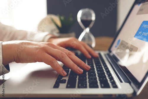 Female young hands with beautiful manicure typing text on laptop at the desk.