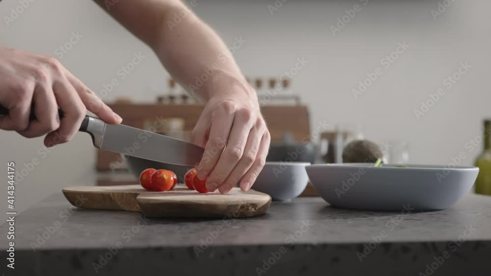 Slow motion orb shot man cut cherry tomato for salad on kitchen countertop Slow motion orb shot man cut cherry tomato for salad on kitchen countertop