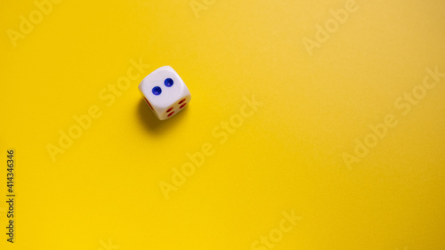White dice with round dots number two on yellow background close-up. Concept of gambling and chance