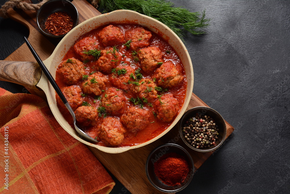 Boulettes de Poisson, Fried Fish Balls in Tomato Sauce in a white dish on a concrete table with ingredients Boulettes de Poisson, Fried Fish Balls in Tomato Sauce in a white dish on a concrete table with ingredients