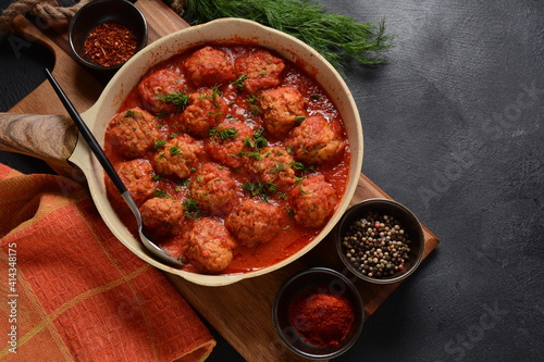 Boulettes de Poisson, Fried Fish Balls in Tomato Sauce in a white dish on a concrete table with ingredients photo