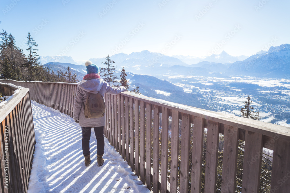 Fototapeta premium Happy young woman is raising her hands on the mountain, enjoying the view over Salzburg. Winter time on Gaisberg, Salzburg, Austria