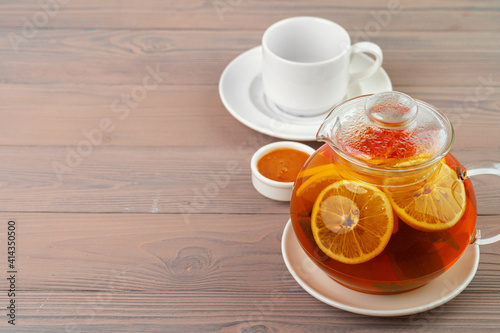 Glass teapot with black tea and pieces of citrus