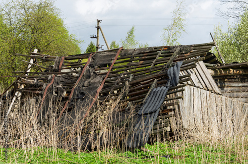 Old roof of a village shed in an abandoned and overgrown village without people (Pskov region, Russia)