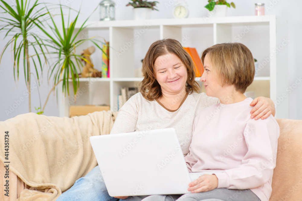 Happy lesbian couple embracing and using laptop at home. Lesbian couple concept Happy lesbian couple embracing and using laptop at home. Lesbian couple concept