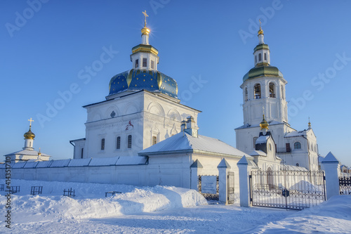 View of the ensemble of churches with golden domes on a frosty winter day. On the fence there is an inscription "Holy Znamensky Abalak Monastery in 1636 - the construction of the first temple" 