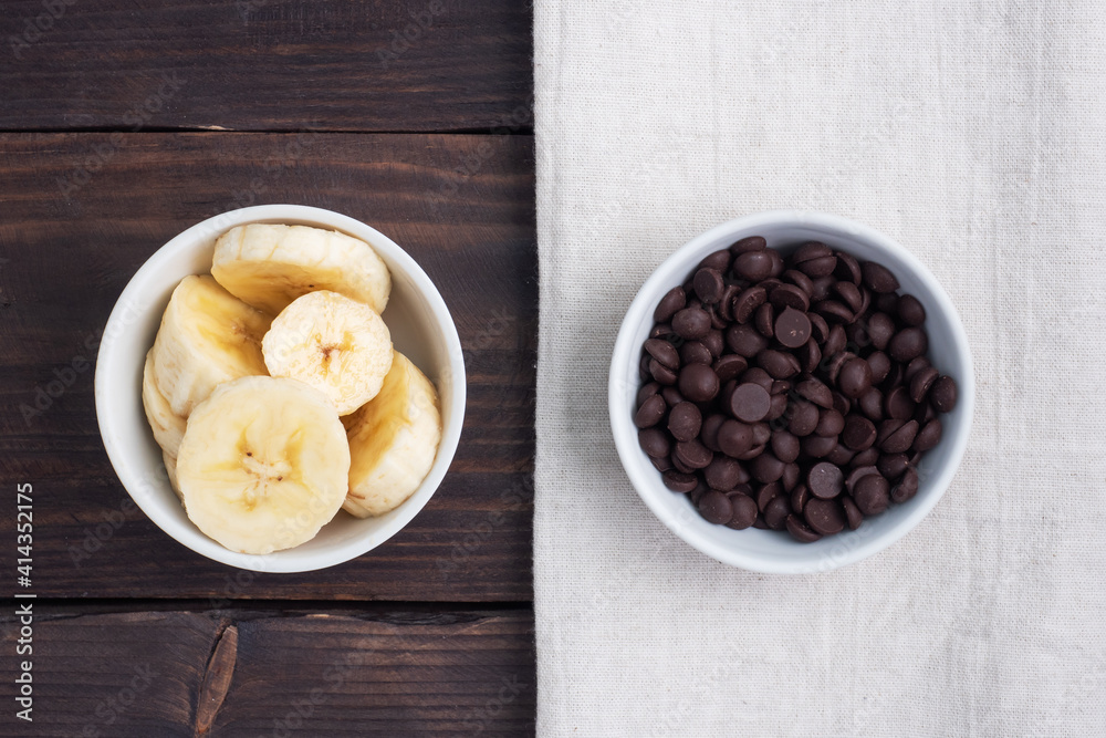 Slices of sliced banana and chocolate drops in a plate. Ingredients for dessert, concept Slices of sliced banana and chocolate drops in a plate. Ingredients for dessert, concept