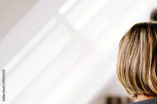 back side headshot of brown haired woman in front of diagonal light