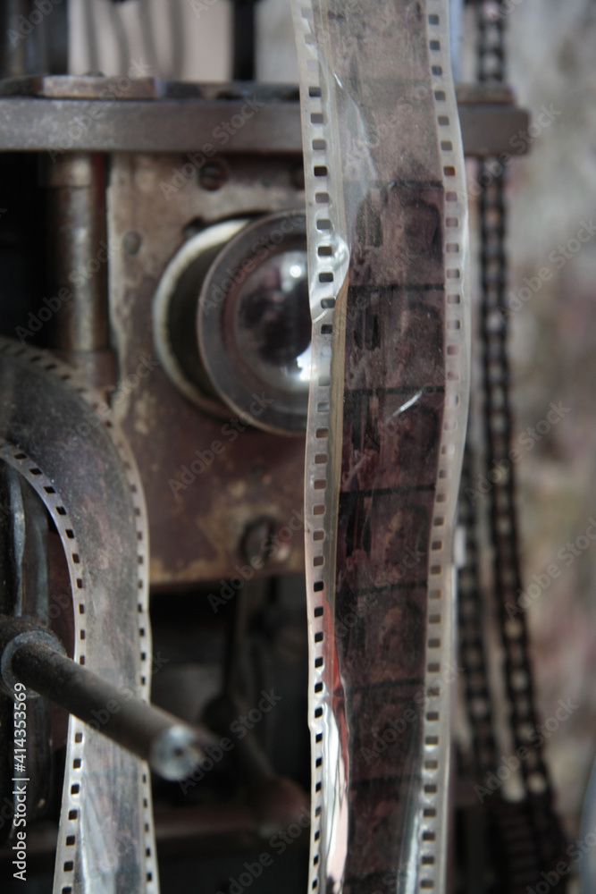 Old film in the foreground, on an antique movie camera. Vintage cinema concept