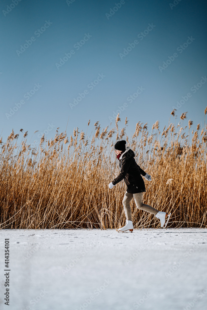 Young woman ice skating outdoors on a pond. Woman figure skating on frozen lake.