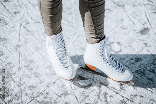 Young woman ice skating outdoors on a pond on a freezing winter day. Detail of skate shoes.