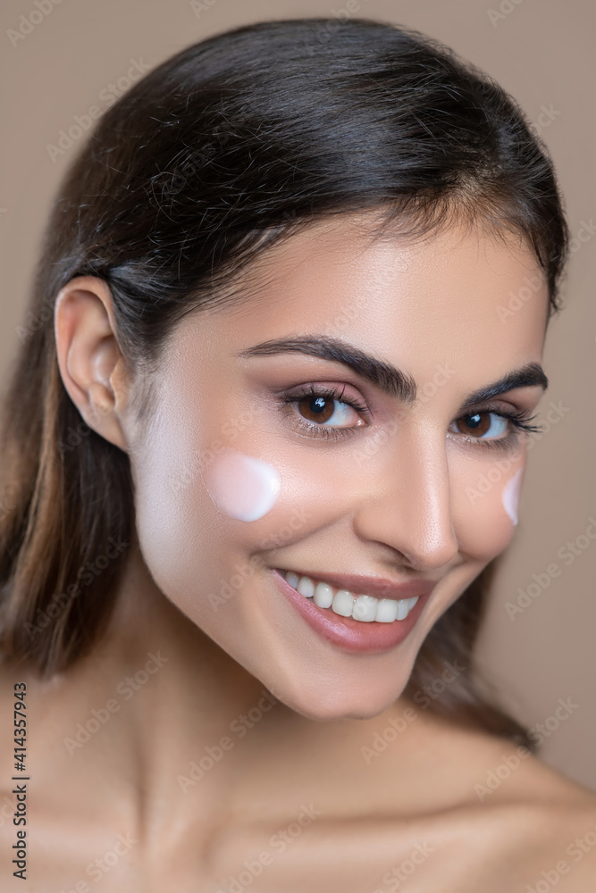 Close-up face of beautiful woman with cream on cheek Close-up face of beautiful woman with cream on cheek