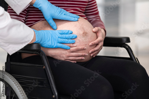 Pregnant woman has her belly checked by a doctor's hands