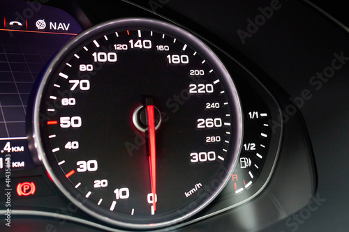 Electronic dashboard of modern luxury car view from aside. Speedometer shows speed in kilometers per hour and fuel control, parking and GPS system alert with copyspace.