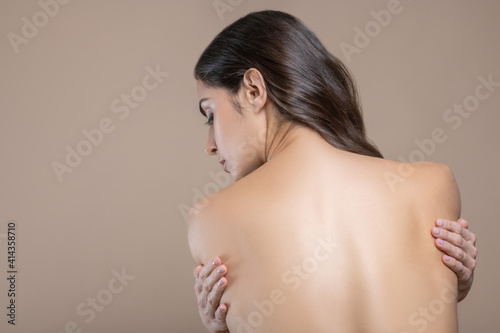 Woman with naked back on beige background