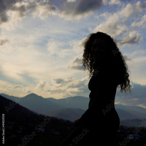silhouette of a girl climbs to the top of a mountain at sunset © Artem