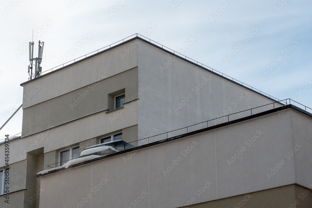 View of the facade of a modern concrete building or office center. The roofs of the buildings are covered with snow and ice after a big snowfall. Modern 5g antenna on the roof of the business center View of the facade of a modern concrete building or office center. The roofs of the buildings are covered with snow and ice after a big snowfall. Modern 5g antenna on the roof of the business center