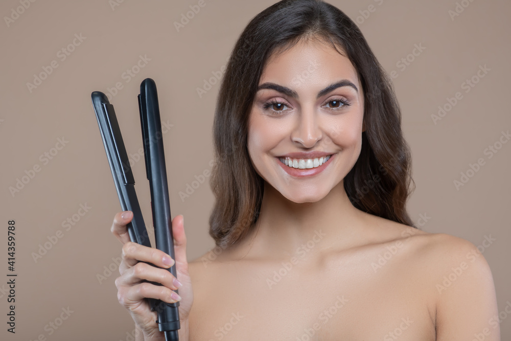 Young woman with bare shoulders with flat iron Young woman with bare shoulders with flat iron