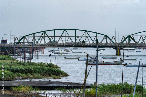 View of river and steel truss bridge in countryside, Japan.