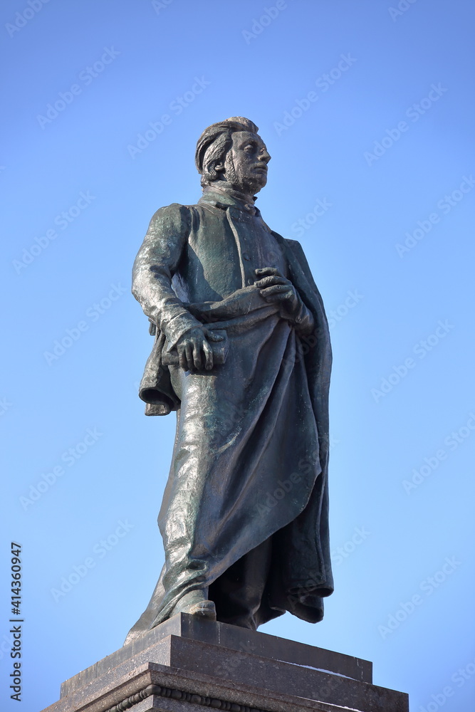 statue monument of Adam Mickiewicz, famous Polish romantic poet, Krakow city center, against blue sky	