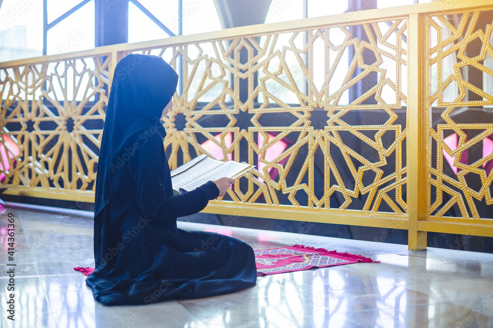 Asian young muslim woman reading quran in mosque after praying.