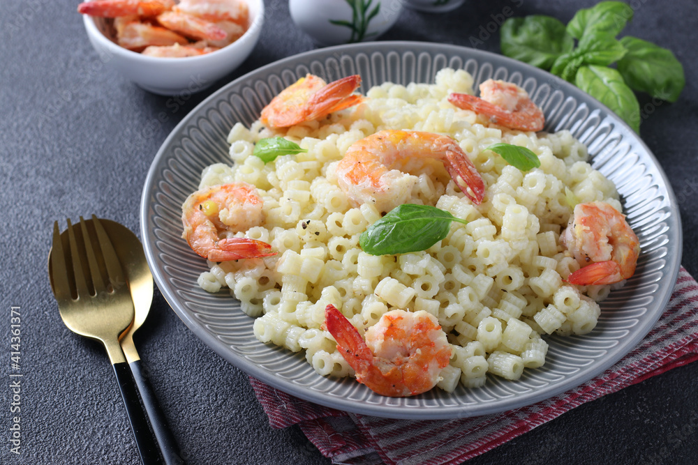 Italian ditalini pasta with shrimps and basil in gray plate on a dark background. Closeup. Italian ditalini pasta with shrimps and basil in gray plate on a dark background. Closeup.
