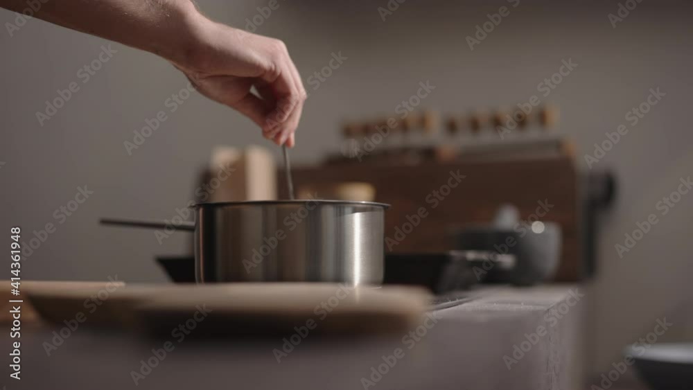 Slow motion man hand stir fettuccine in boiling water in saucepan Slow motion man hand stir fettuccine in boiling water in saucepan