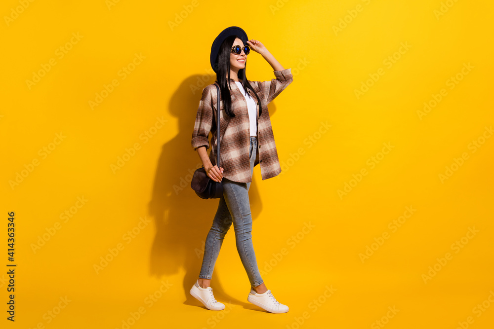 Full length profile side photo of young girl happy smile go walk trip look empty space isolated over yellow color background Full length profile side photo of young girl happy smile go walk trip look empty space isolated over yellow color background