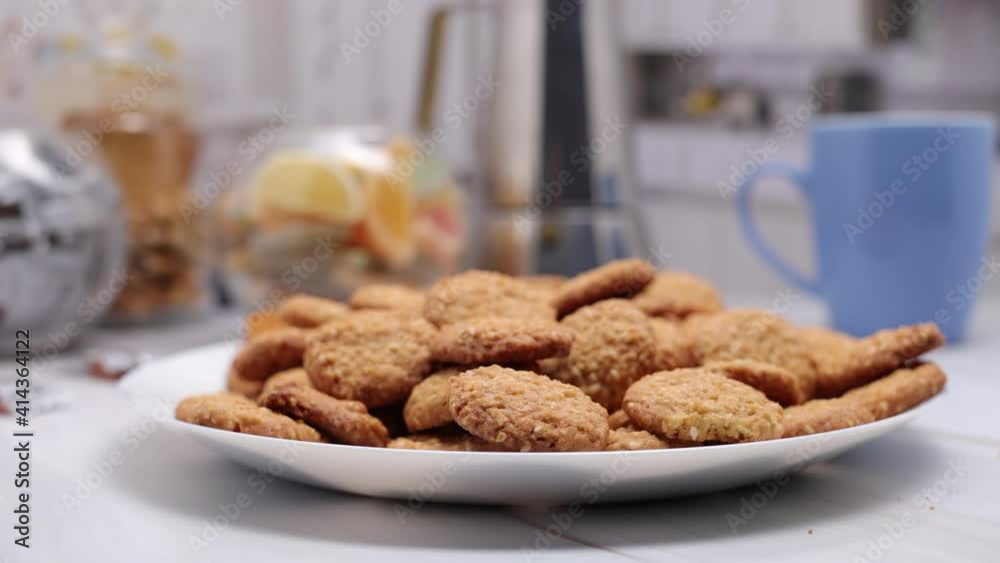Butter Cookies With Sesame Seeds On White Plate On Kitchen Table With A Blue Cup, Slices Of Marmalade And Sweets. Zoom In Dolly Slider Shot. Butter Cookies With Sesame Seeds On White Plate On Kitchen Table With A Blue Cup, Slices Of Marmalade And Sweets. Zoom In Dolly Slider Shot.