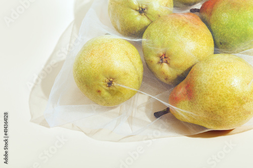 Reusable packaging of products by weight. Pears in a reusable bag close up on a pink background