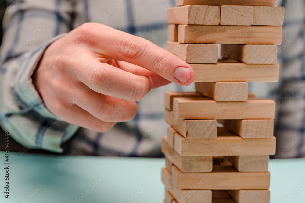 Business man in a shirt builds a tower of wooden blocks as a symbol of development and planning in business, a strategy for success Business man in a shirt builds a tower of wooden blocks as a symbol of development and planning in business, a strategy for success