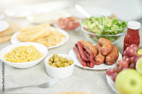 Traditional food. Close up shot of Latin style breakfast with corn, olives, salad and meat on the bright white kitchen table