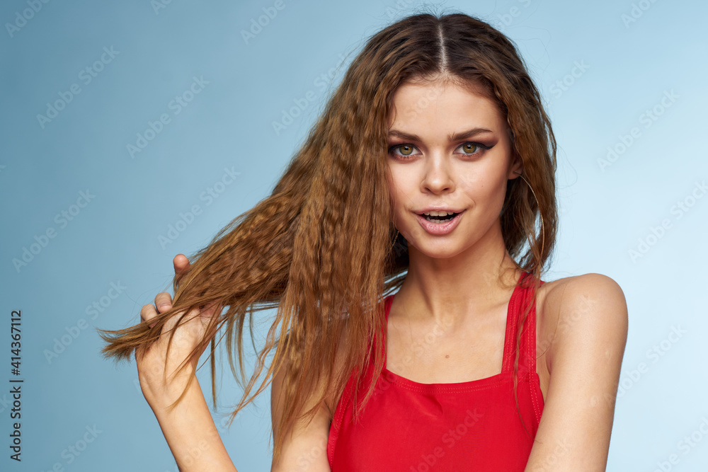 Woman with wavy hair attractive look Red tank top blue background Woman with wavy hair attractive look Red tank top blue background