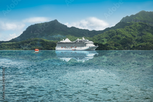 Luxurious cruise ship reflecting in the waters of a beautiful bay of the Leeward Islands in French Polynesia.