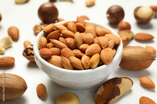 Bowl with apricot seeds and different nuts on white background