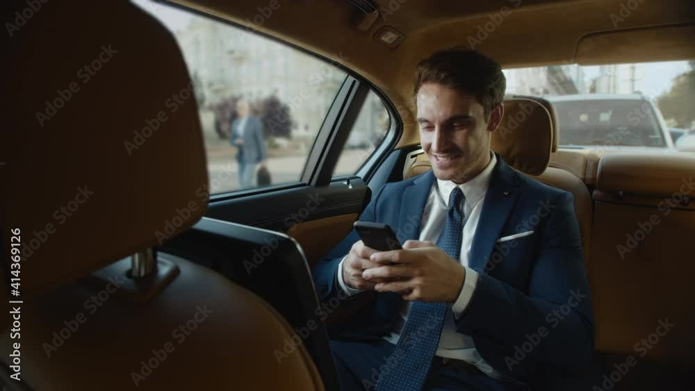 Happy male professional writing message on smartphone in business car. Happy male professional writing message on smartphone in business car.