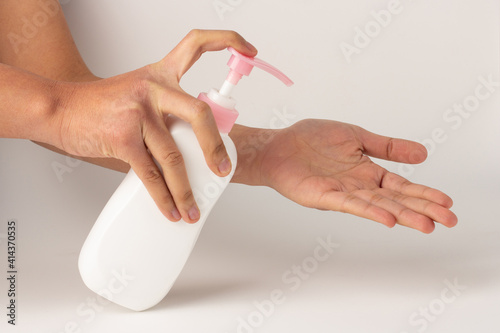 The hand was holding the pump bottle and pressing the lotion onto the palm.