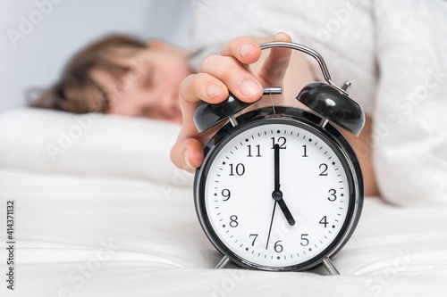 Sleeping woman on pillow with alarm clock before waking up